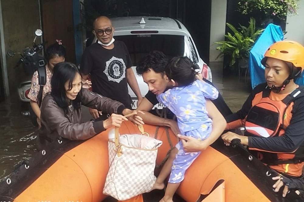 In this photo released by Indonesia's National Search and Rescue Agency (BASARNAS), rescuers evacuate residents from their flooded home in Denpasar, Bali, Indonesia Wednesday, Sept. 10, 2025. (BASARNAS via AP)