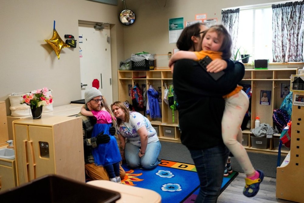 FILE - Olivia Starr clings to her father, Thaxter Hall, as Associate Educator Jessica Clark works to comfort her as she is dropped off for the last day of school at the Meadow Lakes CCS Early Learning, a Head Start center, May 8, 2024, in Wasilla, Alaska. (AP Photo/Lindsey Wasson, File)