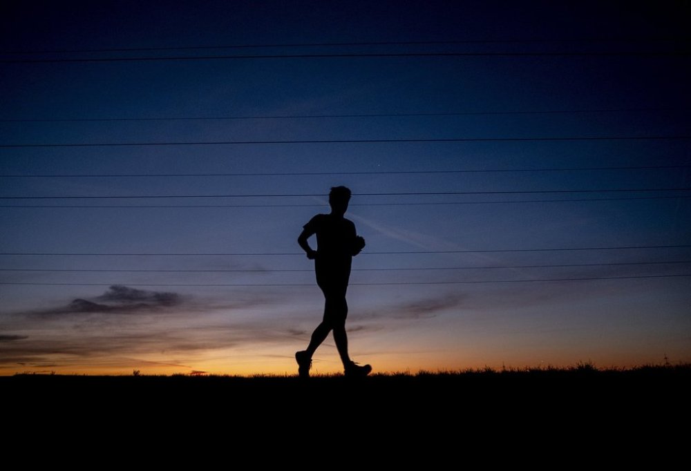 FILE - A man runs on a small road in the outskirts of Frankfurt, Germany, before sunrise on Sept. 8, 2020. (AP Photo/Michael Probst, File)