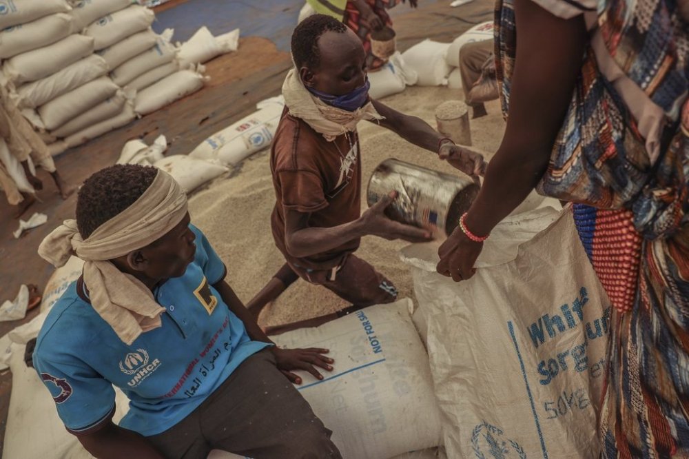 Porters pour sorghum grain into sacks at a food distribution in Gendrassa Refugee Camp, Maban, South Sudan, Aug 20, 2025. (AP Photo/Caitlin Kelly)