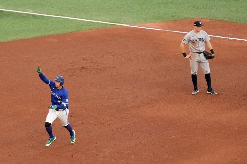Blue Jays designated hitter George Springer (4) celebrates as he rounds the bases following his solo home run as New York Yankees first baseman Ben Rice (22) looks on during the fifth inning of a MLB American League Division Series game in Toronto on Oct. 5, 2025. THE CANADIAN PRESS/Chris Young