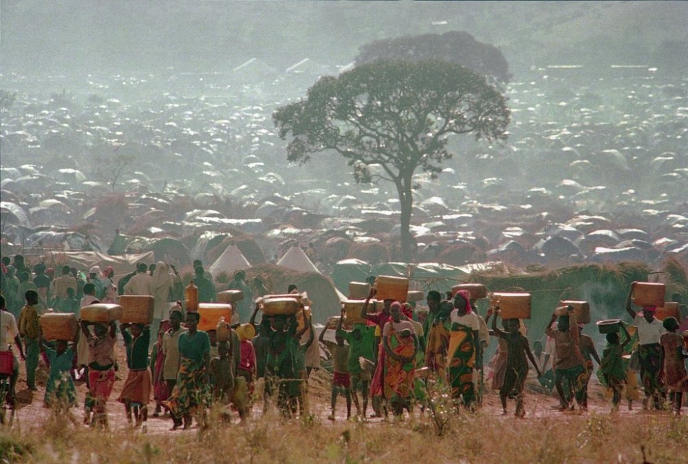 FILE - Refugees who fled the ethnic bloodbath in neighboring Rwanda carry water containers back to their huts at the Benaco refugee camp in Tanzania, near the border with Rwanda, May 17, 1994. (AP Photo/Karsten Thielker, File)
