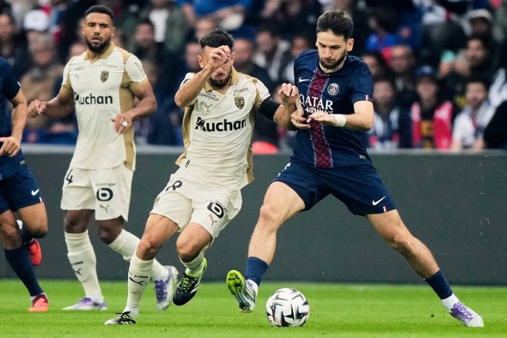 Lens' Adrien Thomasson, left, challenges for the ball with PSG's Khvicha Kvaratskhelia, right, during the French League One soccer match between Paris Saint-Germain and Lens at the Parc des Princes stadium in Paris, Sunday, Sept. 14, 2025. (AP Photo/Michel Euler)