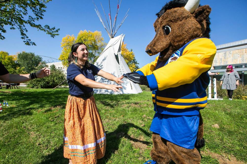 MIKAELA MACKENZIE / FREE PRESS
Mackaila Bruce-Tapley (left), Indigenous Residence Advisor and second-year health sciences student, and Billy the Bison play an Indigenous game at the U of M Indigenous Orientation on Wednesday.