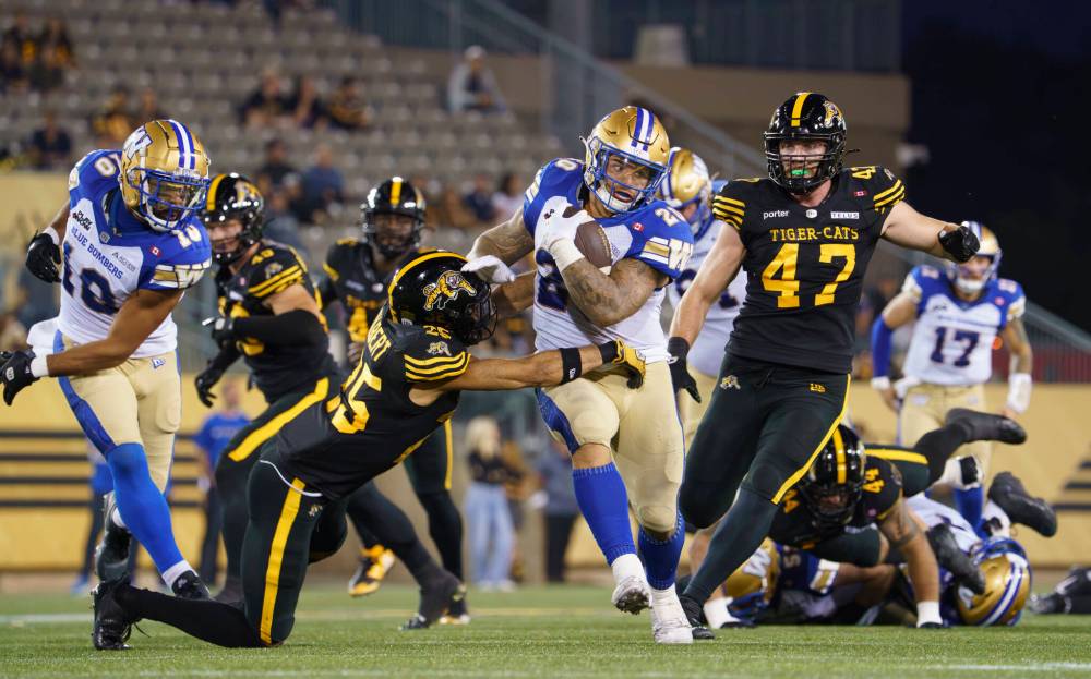 Peter Power / THE CANADIAN PRESS
Winnipeg Blue Bombers running back Brady Oliveira gains some yards on the ground before being tackled by Hamilton Tiger Cats defensive back Destin Talbert during first in Hamilton, Friday.