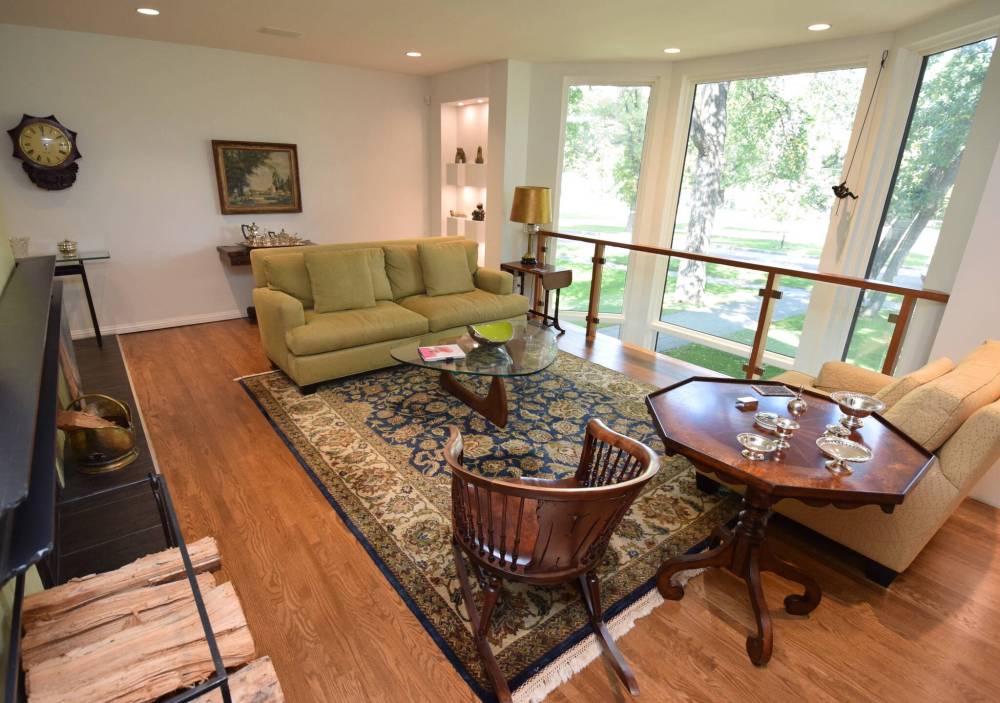 The elegant living room features amazing tree views, a wood-burning fireplace and an illuminated art niche.