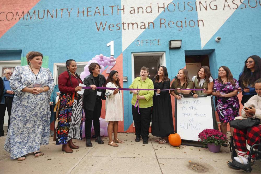 Terry Deller, one of the founding members of the Western Manitoba Women’s Centre, is surrounded by staff while cutting the ribbon during the grand opening Thursday. (Tim Smith / The Brandon Sun)
