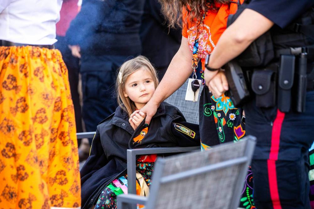 MIKAELA MACKENZIE / FREE PRESS
Three-year-old Katherine Courteau, granddaughter of a residential school survivor and a WPS officer, stays warm by the Winnipeg Police Service sacred fire with her mom, Andrea Gallagher.