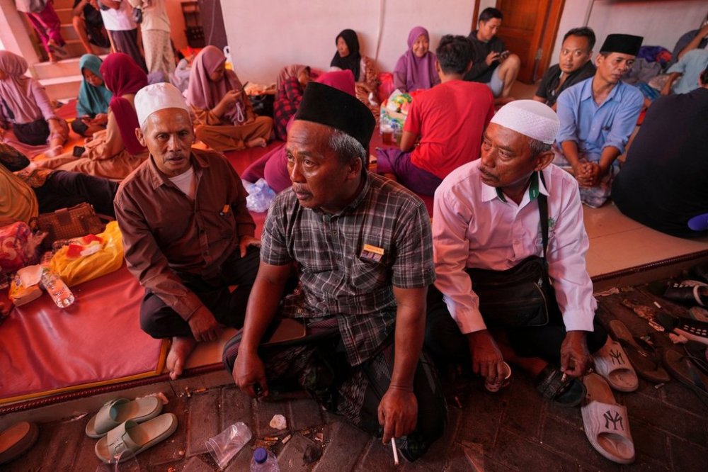 Mohammad Solehoddin, center, whose son has not been accounted for after a building under construction collapsed Monday at an Islamic boarding school, waits with other family members as rescue efforts are underway, in Sidoarjo, East Java, Indonesia, Thursday, Oct. 2, 2025. (AP Photo/Achmad Ibrahim)