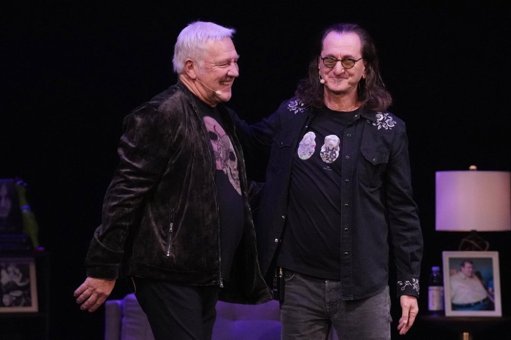 Geddy Lee (right) stands on stage with fellow Rush band member Alex Lifeson, as Lee promotes his book