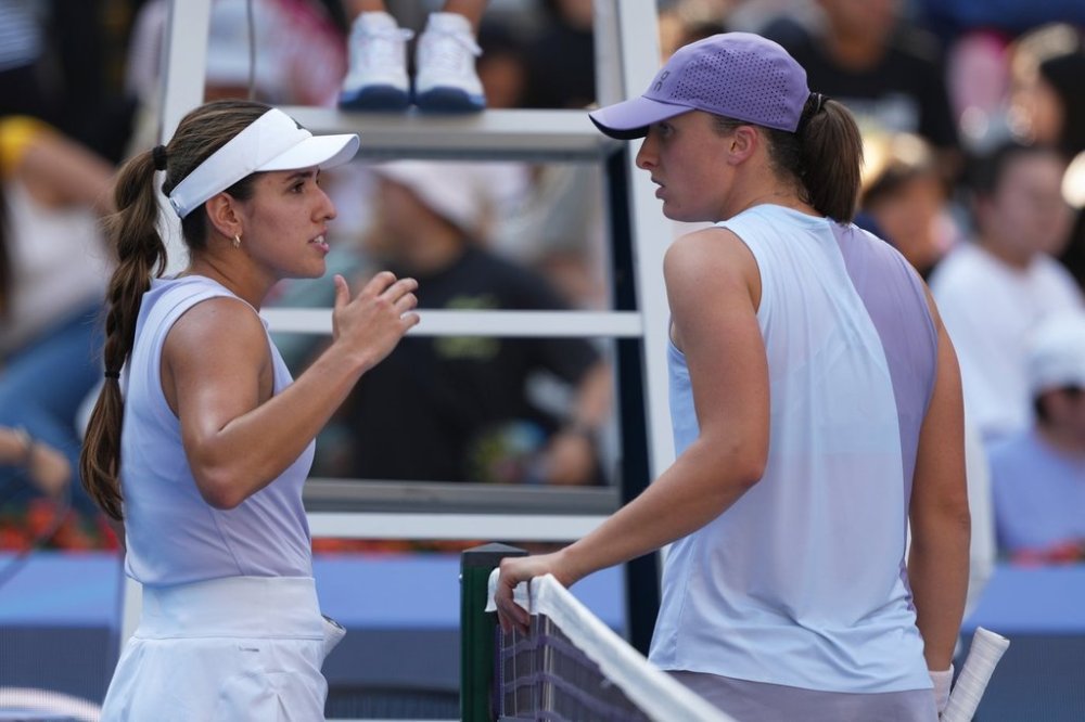 Camila Osorio, of Colombia, left, talks to Iga Swiatek, of Poland after she retired from the women's singles match for the China Open tennis tournament, in Beijing, Monday, Sept. 29, 2025. (AP Photo/Andy Wong)