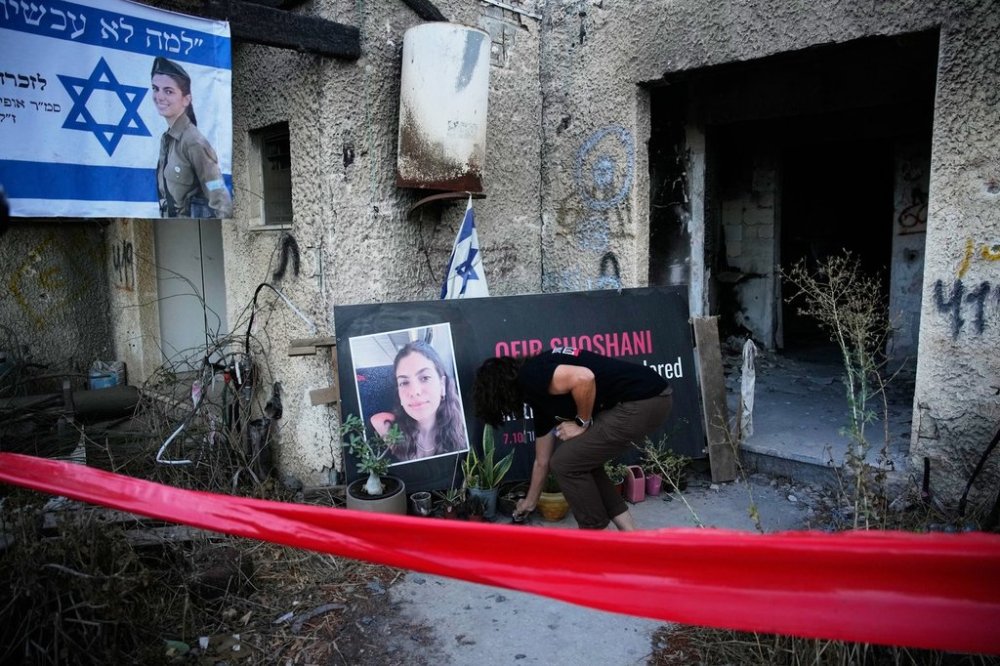 A woman places a candle at a tribute for Ofir Shoshani during a memorial marking two years since the deadly Hamas cross-border attack on Israel, in Kibbutz Kfar Aza, Tuesday, Oct. 7, 2025. (AP Photo/Ohad Zwigenberg)