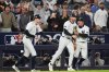 New York Yankees third base Ryan McMahon, center, is congratulated by pitcher Cam Schlittler, left, and shortstop Anthony Volpe after making a catch over the Boston Red Sox dugout during the eighth inning of Game 3 of an American League wild-card baseball playoff series, Thursday, Oct. 2, 2025, in New York. (AP Photo/Frank Franklin II)