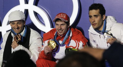 FILE - Russia's gold medal winner Evgeny Ustyugov is flanked by France's silver medal winner Martin Fourcade, right, and Slovakia's bronze medal winner Pavol Hurajt during the medal ceremony for the Men's 15k mass start Biathlon race at the Vancouver 2010 Olympics in Whistler, British Columbia, Canada, Sunday, Feb. 21, 2010. (AP Photo/Dmitry Lovetsky, File)