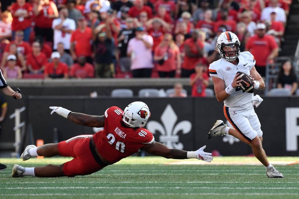 Virginia quarterback Chandler Morris (4) avoids the reach of Louisville Cardinals defensive lineman Rene Konga (90) during the second half of an NCAA college football game in Louisville, Ky., Saturday, Oct. 4, 2025. (AP Photo/Timothy D. Easley)