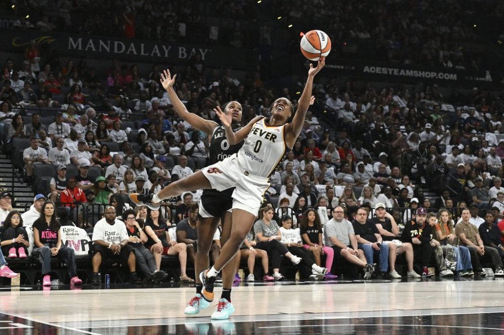 Indiana Fever guard Kelsey Mitchell, right, shoots against Las Vegas Aces guard Jackie Young, left, in the second half of Game 1 of a WNBA basketball playoff semifinals series Sunday, Sept. 21, 2025, in Las Vegas. (AP Photo/Candice Ward)