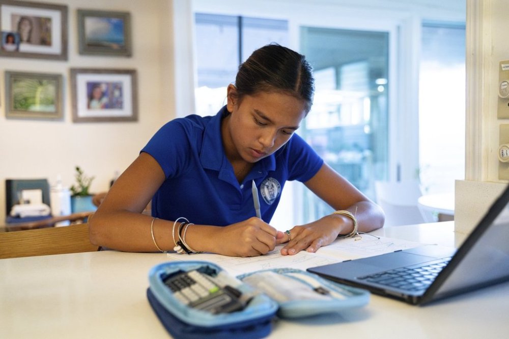 Kapua Ong does math homework at her home in Honolulu, on Thursday, Sept. 11, 2025. (AP Photo/Mengshin Lin)