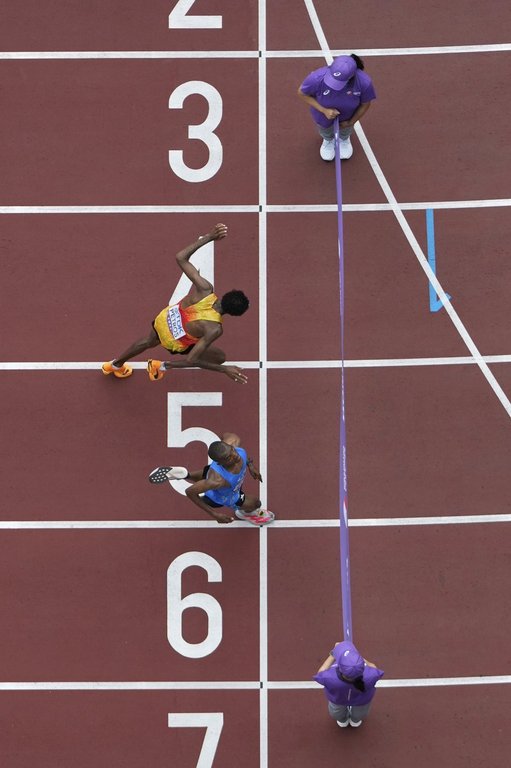 Tanzania's Alphonce Felix Simbu, bottom, crosses the finish line ahead of Germany's Amanal Petros to win the men's marathon at the World Athletics Championships in Tokyo, Monday, Sept. 15, 2025. (AP Photo/Bernat Armangue)