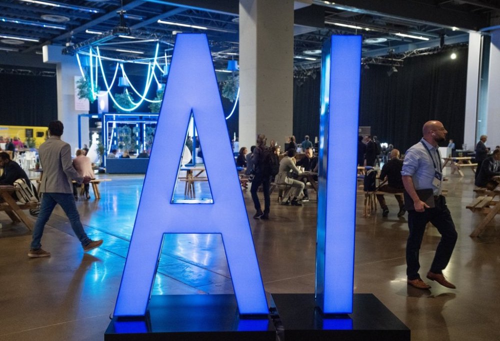 People walk past an illuminated sign at the All In artificial intelligence conference on Thursday, Sept. 28, 2023, in Montreal.THE CANADIAN PRESS/Ryan Remiorz
