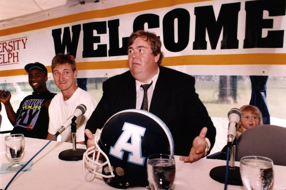 Toronto Argonauts co-owners John Candy, right, and Wayne Gretzky along with player Raghib (Rocket) Ismail talk to reporters at the team's training camp in Guelph, Ont., June 7, 1991. THE CANADIAN PRESS/Hans Deryk