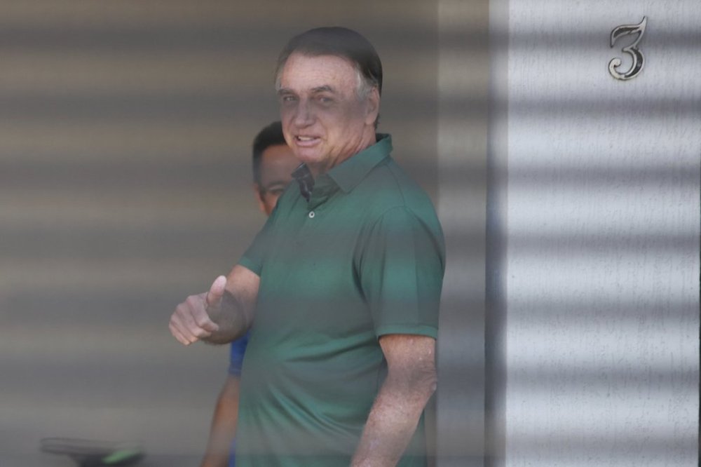 Brazil's former President Jair Bolsonaro flashes a thumbs up while standing at the entrance of his home where he is under house arrest in Brasilia, Brazil, Thursday, Sept. 11, 2025. (AP Photo/Luis Nova)