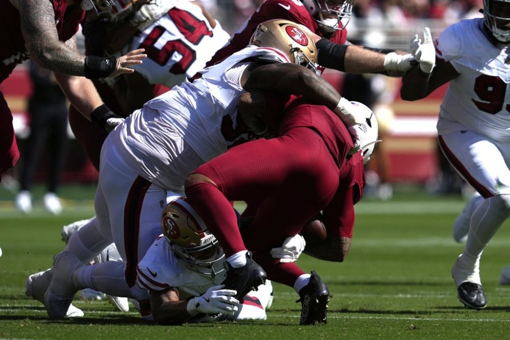 Arizona Cardinals running back James Conner right, is injured while being tackled by San Francisco 49ers defensive tackle Jordan Elliott, top, and cornerback Chase Lucas during the second half of an NFL football game Sunday, Sept. 21, 2025, in Santa Clara, Calif. (AP Photo/Godofredo A. Vásquez)