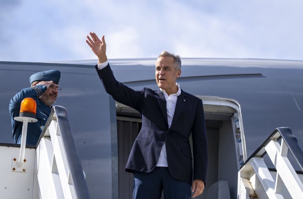 Prime Minister Mark Carney waves as he boards a government plane to head home from Riga, Latvia on Wednesday, Aug. 27, 2025. THE CANADIAN PRESS/Christinne Muschi