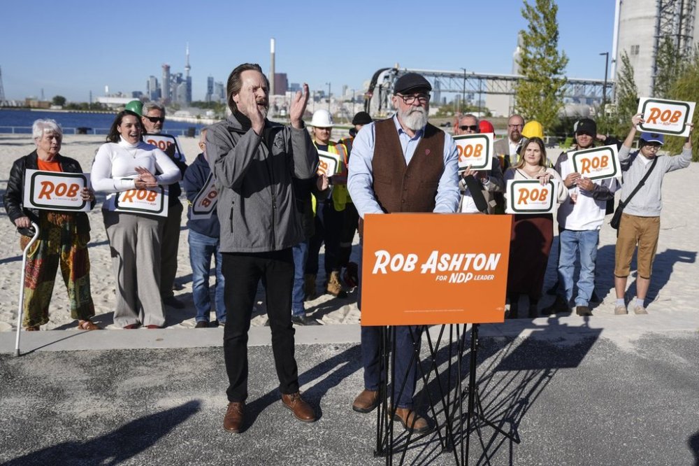 Rob Ashton, standing behind the podium, is joined by supporters in Toronto on Wednesday, Oct. 1, 2025, as he announces he's running for the federal NDP leadership. THE CANADIAN PRESS/Chris Young