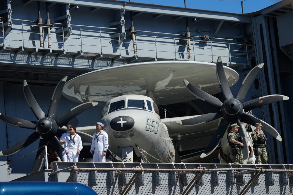 Sailors stand near a E-2 Hawkeye before President Donald Trump arrives to speak during a celebration for the 250th anniversary of the U.S. Navy aboard the USS Harry S. Truman at Naval Station Norfolk, Sunday Oct. 5, 2025 in Norfolk, Va. (AP Photo/Steve Helber)