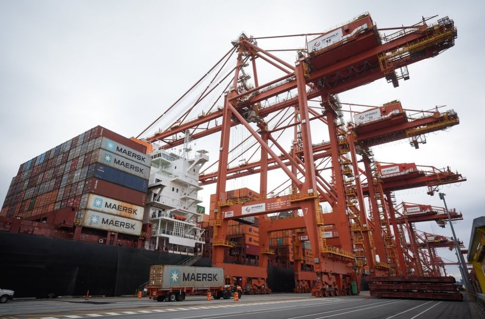 A transport truck carries a cargo container to be loaded on the Hapag-Lloyd container ship Frankfurt Express at the DP World Centerm terminal at port, in Vancouver, on Sunday, Aug. 3, 2025. THE CANADIAN PRESS/Darryl Dyck