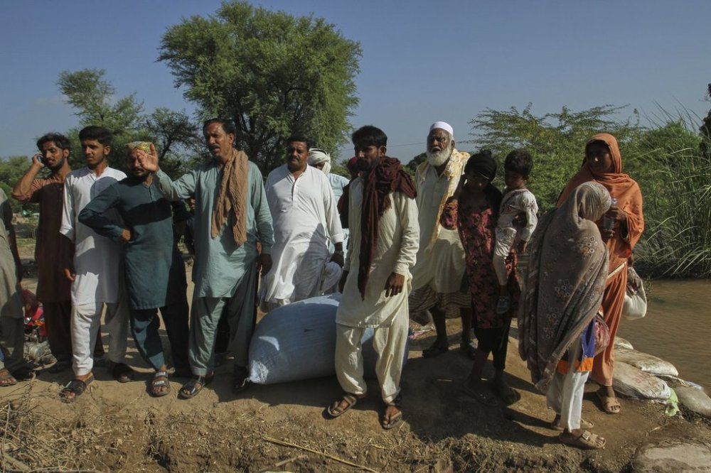 Villagers look to a rescue boat arriving to evacuate them from a flooded area in Muhammad Pur Ghotta in Multan district, Pakistan, Thursday, Sept. 11, 2025. (AP Photo/Asim Tanveer)