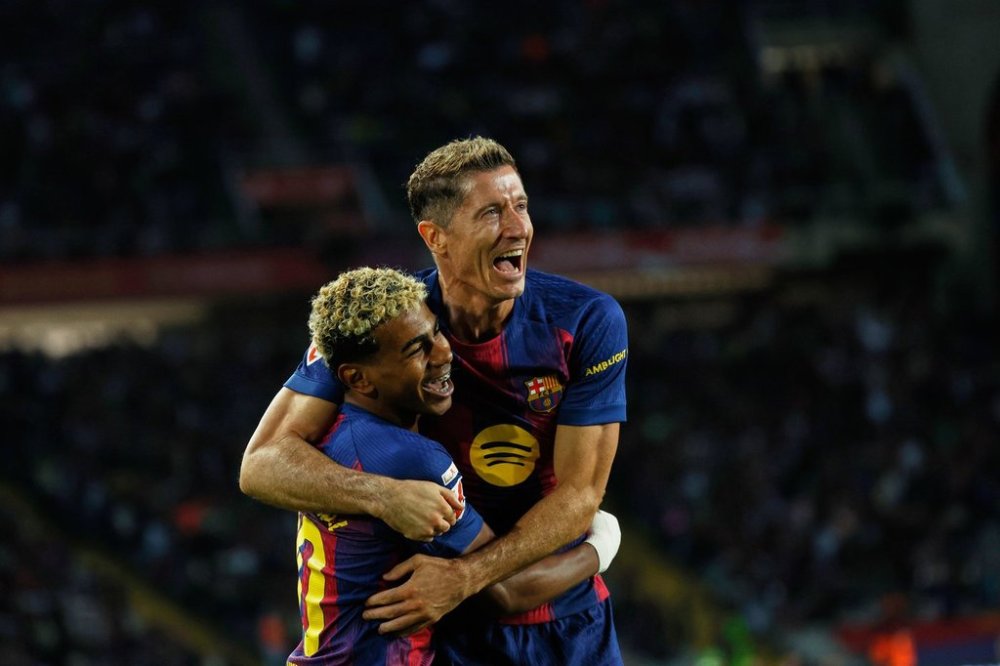 Barcelona's Robert Lewandowski, top, celebrates with Lamine Yamal scoring his side's 2nd goal during a Spanish La Liga soccer match between FC Barcelona and Real Sociedad at the Lluis Companys Olympic Stadium in Barcelona, Spain, Sunday, Sept. 28, 2025. (AP Photo/Joan Monfort)