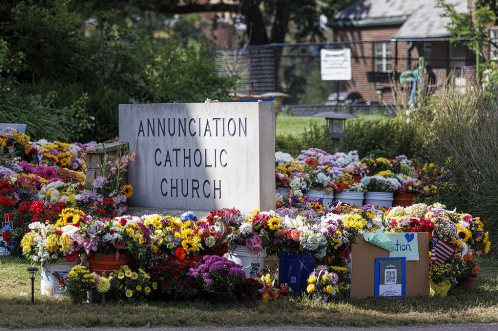 A vibrant memorial of flowers and tributes surrounds a sign for Annunciation Catholic Church in Minneapolis, Minn., on Wednesday, Sept. 3, 2025. (Kerem Yucel/Minnesota Public Radio via AP)