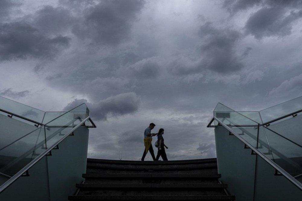 Pedestrians walk along the waterfront of Victoria Harbor ahead of Super Typhoon Ragasa approaches Hong Kong, Tuesday, Sept. 23, 2025. (AP Photo/Chan Long Hei)
