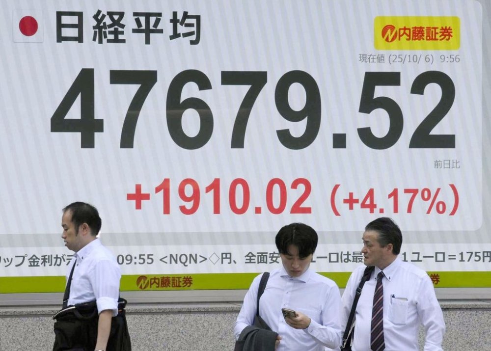 People stand in front of an electronic stock board showing Japan's Nikkei 225 index at a securities firm in Tokyo, Monday, Oct. 6, 2025. (Kyodo News via AP)