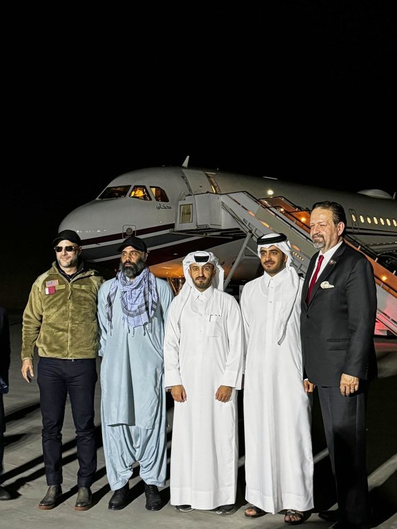 In this photo released by Qatar's Foreign Ministry, U.S. citizen Amir Amiri, second from left, poses before boarding a plane in Kabul, Afghanistan, on Sunday, Sept. 28, 2025, after being released from an Afghan prison. With him, from right, Deputy Assistant to the U.S. President Sebastian Gorka, an unidentified Qatari diplomat, Charge d'Affaires of the Embassy of the State of Qatar in Afghanistan Dr. Mirdef Al Qashouti, centre, and, left, U.S. Special Envoy for Hostage Response Adam Boehler. (Qatar Foreign Ministry via AP)