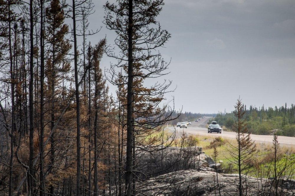 Evacuees from Yellowknife make their way along Highway 3 at the edge of a burned forest on their way into Fort Providence, N.W.T., Thursday, Aug. 17, 2023. THE CANADIAN PRESS/Bill Braden