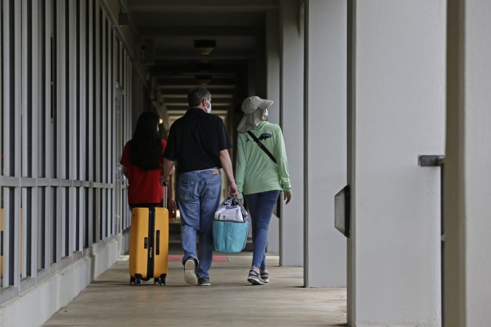 FILE - A family walks down a corridor at Lee Hall as college students begin moving in for the fall semester at N.C. State University in Raleigh, N.C., July 31, 2020. (AP Photo/Gerry Broome, File)