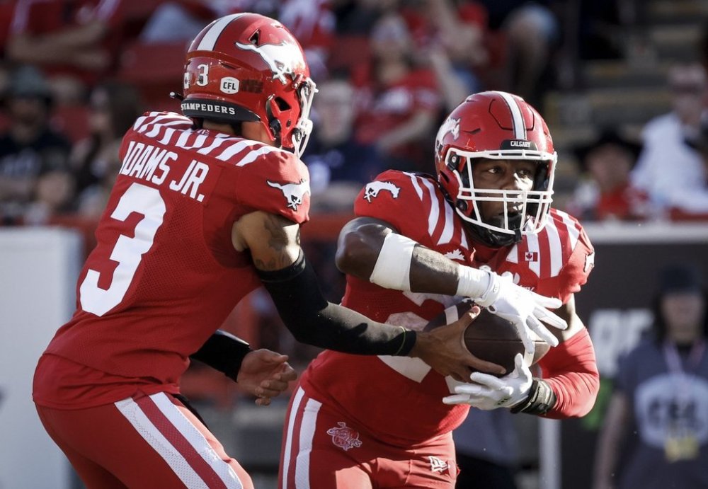 Calgary Stampeders quarterback Vernon Adams Jr., left, hands the ball off to Dedrick Mills during first half CFL football action against the Montreal Alouettes in Calgary, Thursday, July 24, 2025.THE CANADIAN PRESS/Jeff McIntosh