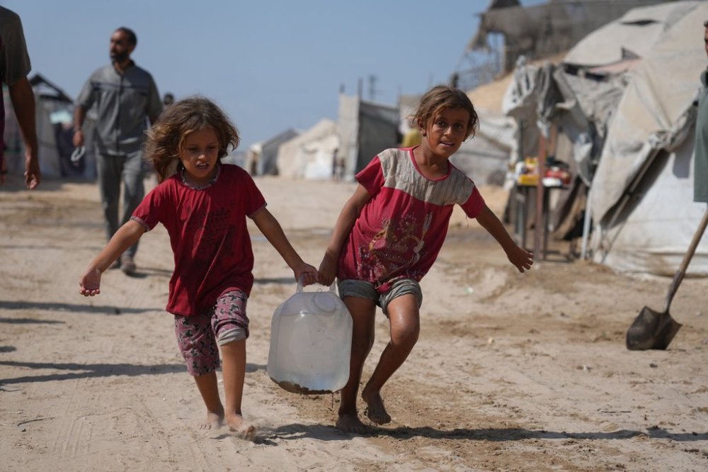 Displaced Palestinians girls carry a jerry can after collecting water from a distribution point at a tent camp in Muwasi, an area that Israel has designated as a safe zone, in Khan Younis southern Gaza Strip, Monday, Sept. 29, 2025. (AP Photo/Jehad Alshrafi)