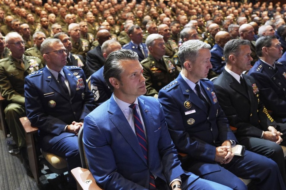 Defense Secretary Pete Hegseth, center, sitting with Chairman of the Joint Chiefs of Staff Air Force Gen. Dan Caine, third from right, and U.S. military senior leadership as they listen to President Donald Trump speaks at Marine Corps Base Quantico, Tuesday, Sept. 30, 2025 in Quantico, Va. (AP Photo/Evan Vucci)