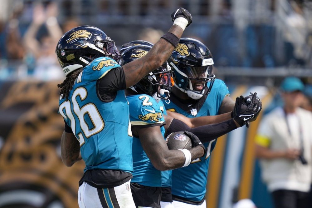 Jacksonville Jaguars cornerback Jourdan Lewis, center, celebrates an interception with teammates safety Antonio Johnson (26) and defensive end Josh Hines-Allen during the second half of an NFL football game against the Houston Texans Sunday, Sept. 21, 2025, in Jacksonville, Fla. (AP Photo/John Raoux)