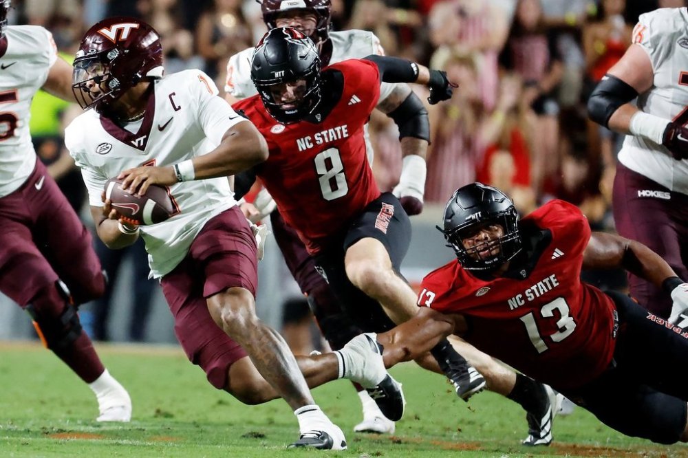 Virginia Tech quarterback Kyron Drones (1) avoids the rush of North Carolina State defensive end Travali Price (13), and Isaiah Crowell (8) during the first half of an NCAA college football game in Raleigh, N.C., Saturday, Sept. 27, 2025. (AP Photo/Karl DeBlaker)