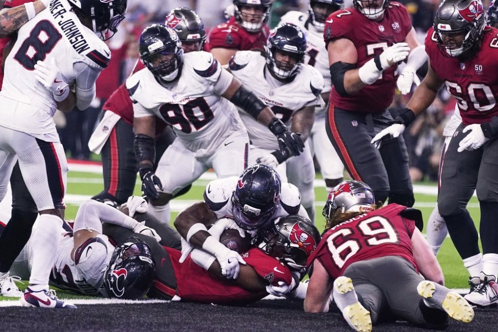 Tampa Bay Buccaneers running back Rachaad White, center bottom, scores a touchdown on a run as Houston Texans' C.J. Gardner-Johnson (8), Sheldon Rankins (90) and others look on in the second half of an NFL football game Monday, Sept. 15, 2025, in Houston, Texas. (AP Photo/Eric Christian Smith)