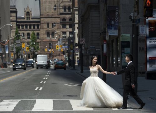 A couple poses for photographs in their wedding outfits during photo shoot in the middle of a street in Toronto on Friday, June 5, 2020. THE CANADIAN PRESS/Nathan Denette