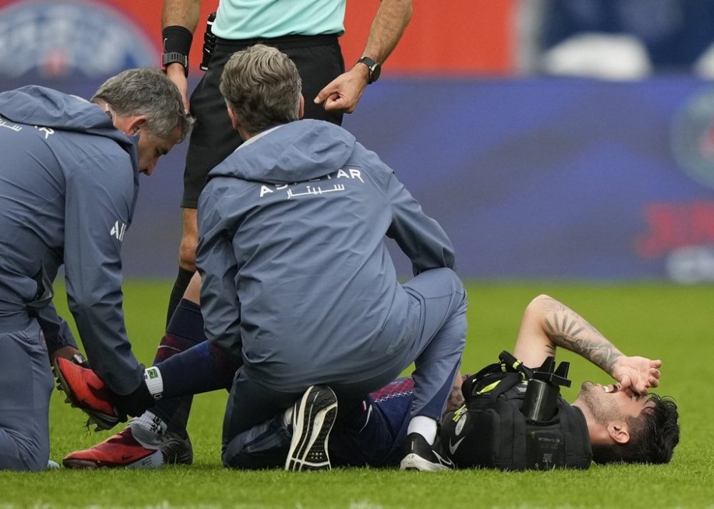 Medics taking care of PSG's Lucas Beraldo who was injured during the French League One soccer match between Paris Saint-Germain and Lens at the Parc des Princes stadium in Paris, Sunday, Sept. 14, 2025. (AP Photo/Michel Euler)