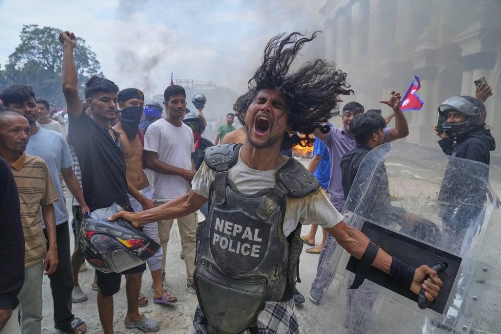 A protester wearing a policeman flak jacket and carrying a shield shouts slogans at the Singha Durbar, the seat of Nepal's government's various ministries and offices during a protest against social media ban and corruption in Kathmandu, Nepal, Tuesday, Sept. 9, 2025. (AP Photo/Niranjan Shrestha)
