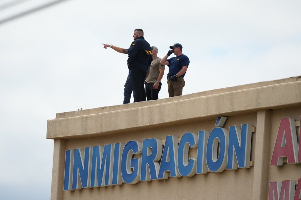 Law enforcement agents look around the roof of an apartment building near the scene of a shooting at a U.S. Immigration and Customs Enforcement office in Dallas on Wednesday, Sept. 24, 2025. (AP Photo/Julio Cortez)