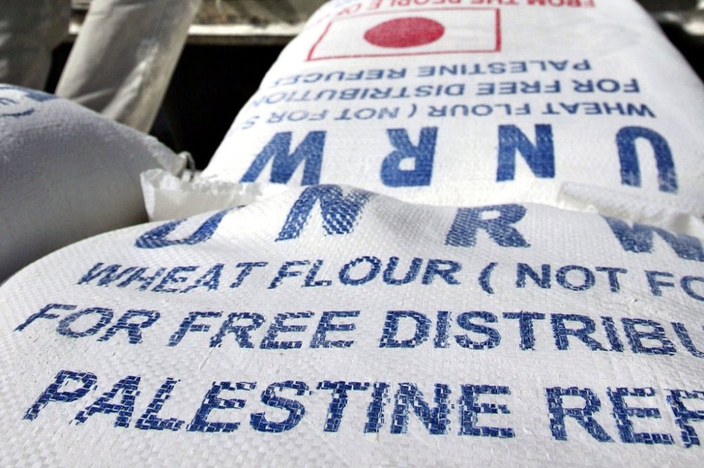 FILE - Sacks of flour are unloaded from a truck as residents receive their monthly food supplies from the UN Relief and Works Agency (UNRWA) at a warehouse at the Jebaliya refugee camp in the northern Gaza Strip, on Thursday, April 13, 2006. (AP Photo/Emilio Morenatti, File)