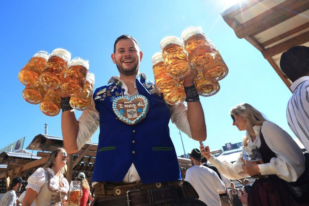 A waiter carries mugs of beer into the Hacker tent on the first day of Oktoberfest on Munich's Theresienwiese, Germany, Saturday, Sept. 20, 2025. (Karl-Josef Hildenbrand/dpa via AP)